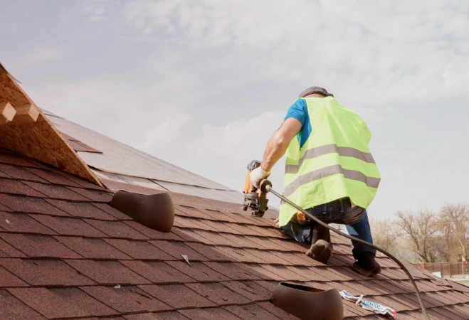 worker installing new asphalt shingles as replacement